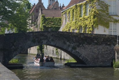 people riding on boat under bridge during daytime