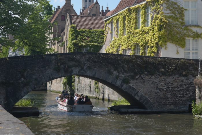 people riding on boat under bridge during daytime