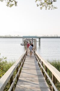 woman in white shirt and blue denim jeans standing on wooden dock during daytime